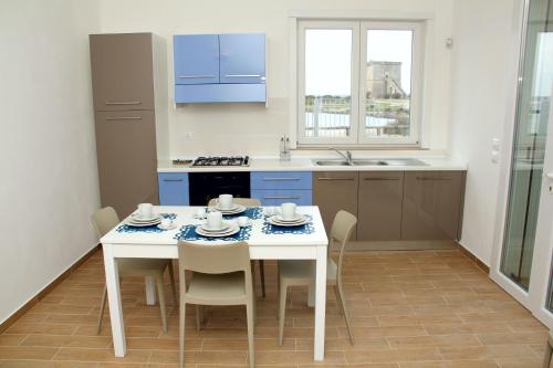 cocina con mesa blanca con sillas y fregadero en Altomare Case Vacanza, en Torre Lapillo