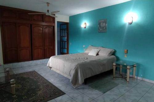 1 dormitorio con cama y pared azul en Casa Las Palmas Barra de Navidad, Jalisco. en Barra de Navidad