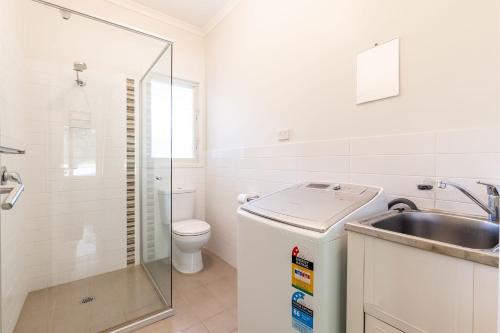 a white bathroom with a sink and a toilet at Florida 1 2 min walk to beach shops and restaurants in Shoal Bay
