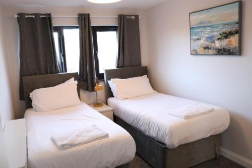 two beds in a room with two windows at Garland Modern Apartment with Private Garden & Parking Dartford 5 in Kent