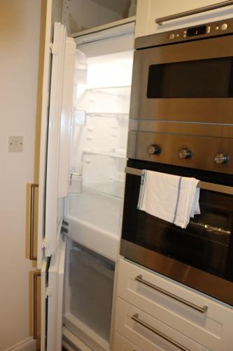 an empty refrigerator with its door open in a kitchen at Garland Modern Apartment with Private Garden & Parking Dartford 5 in Kent