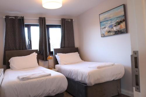 a room with two beds and a painting on the wall at Garland Modern Apartment with Private Garden & Parking Dartford 5 in Kent