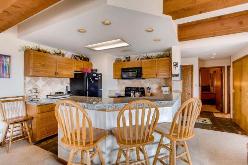 a kitchen with wooden cabinets and a bar with chairs at Rustic 3 Br Condominium Condo in Crested Butte