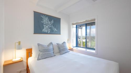 a bedroom with a white bed and a window at Coast Yamba - Adults Only in Yamba
