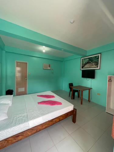 Medano Sunset Resort في مامباجاو: غرفة نوم بجدران خضراء وسرير مع طاولة