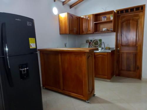 a kitchen with wooden cabinets and a black refrigerator at Apartamentos con estacionamiento cerca al parque in Támesis
