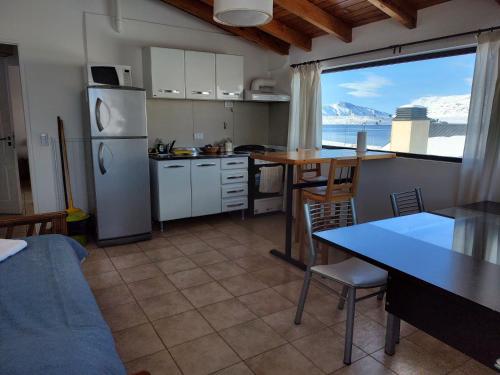 a kitchen with a refrigerator and a table with a dining table at Cerro Pirámide Alojamiento in Caviahue