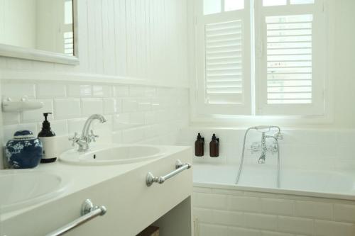 La salle de bains blanche est pourvue d'un lavabo et d'une baignoire. dans l'établissement Maison Victoire, Pointe-à-Pitre, à Pointe-à-Pitre
