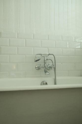 a bath tub with a faucet on a white wall at Maison Victoire, boutique hôtel - Pointe-à-Pitre in Pointe-à-Pitre