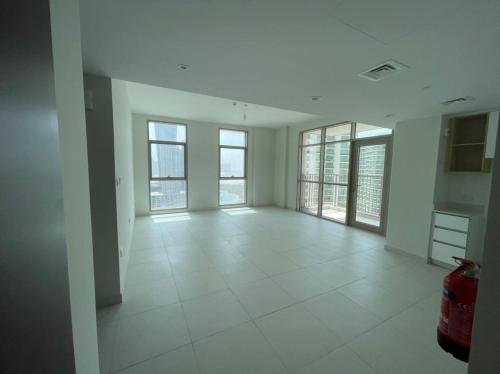 una stanza vuota con finestre e pavimento piastrellato bianco di Luxury shared next to Airport a Abu Dhabi