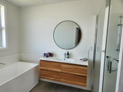 y baño con bañera, lavabo y espejo. en Beautifully renovated townhouse, easy walk to CBD en Blenheim