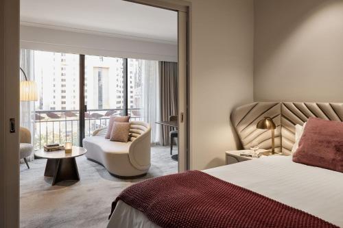 a hotel room with a bed and a chair and a balcony at The Playford Adelaide - MGallery in Adelaide
