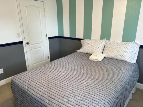 Bett in einem Zimmer mit gestreifter Wand in der Unterkunft Serenity in Fresno