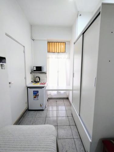 una pequeña cocina con nevera y ventana en Habitacion con baño privado en Córdoba