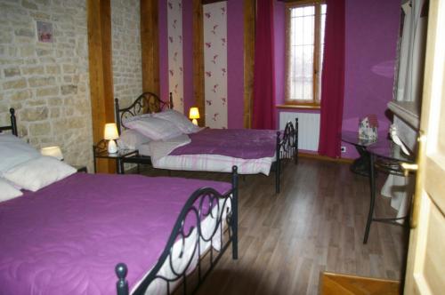 Cette chambre comprend 2 lits dans une chambre dotée de murs violets et de parquet. dans l'établissement Gite au Chalet, à Laferté-sur-Aube