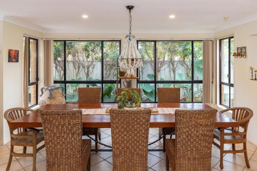a dining room with a wooden table and chairs at 21 Cedar Grove in Forster