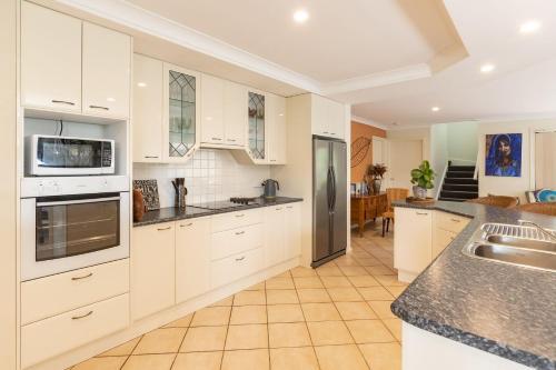 a kitchen with white cabinets and stainless steel appliances at 21 Cedar Grove in Forster
