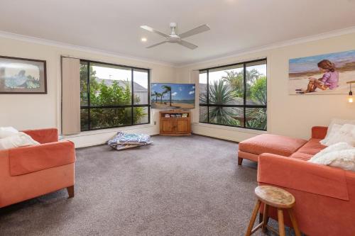a living room with two orange couches and windows at 21 Cedar Grove in Forster