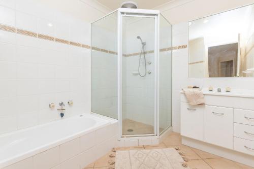 uma casa de banho branca com uma banheira e um chuveiro em 21 Cedar Grove em Forster