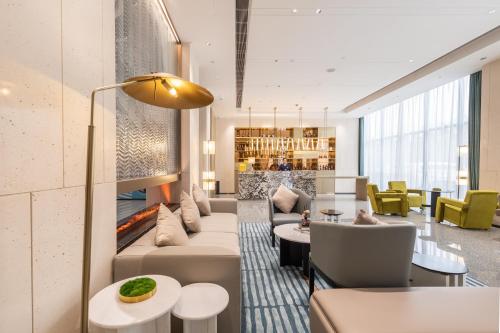 a hotel lobby with a couch and chairs and a fireplace at Guangzhou Baiyun Airport MeHood Liz Hotel Free Shuttle Bus to Canton Fair and to Airport in Guangzhou