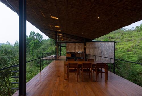 a room with a table and chairs on a deck at Kurunduketiya Private Rainforest Resort in Kalawana