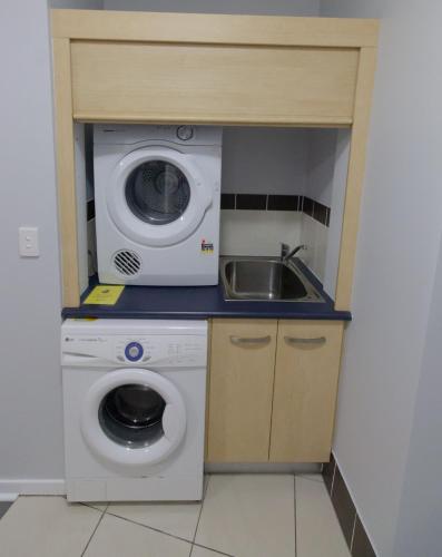 a kitchen with a washing machine and a sink at Caloundra Central Apartment Hotel Official in Caloundra
