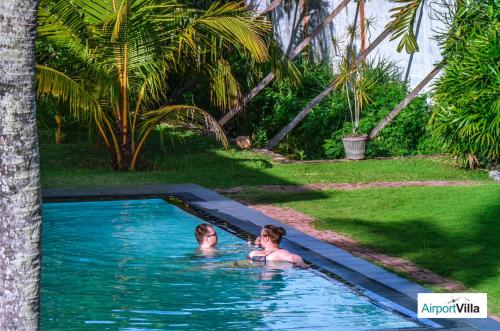 two people in a swimming pool in a yard at Airport Villa in Katunayake