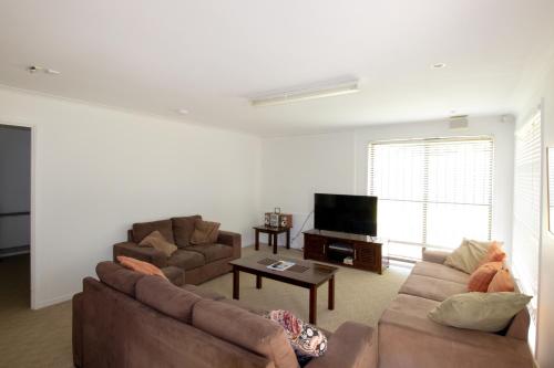 a living room with two couches and a tv at Caloundra Central Apartment Hotel Official in Caloundra