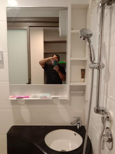 a man taking a picture of a mirror in a bathroom at APARTEMEN SKY HOUSE BSD in Samporo