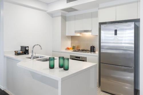 a white kitchen with a sink and a refrigerator at Meriton Suites Herschel Street, Brisbane in Brisbane
