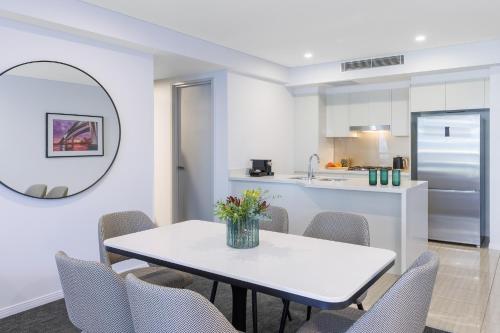 a kitchen and dining room with a table and chairs at Meriton Suites Herschel Street, Brisbane in Brisbane