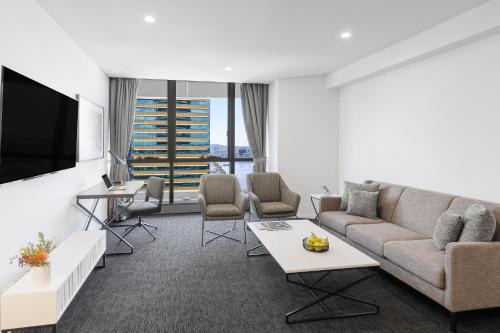 a living room with a couch and a tv at Meriton Suites Herschel Street, Brisbane in Brisbane