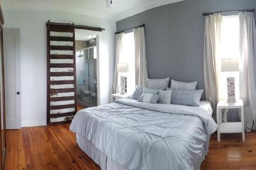 een witte slaapkamer met een bed en een spiegel bij Fully Furnished Charming and Quaint New Orleans Cottage in Arabi