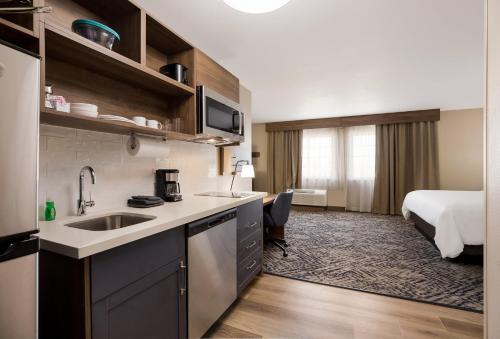 a kitchen with a sink and a room with a bed at Candlewood Suites Lafayette - River Ranch, an IHG Hotel in Lafayette