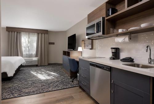 a kitchen with a sink and a bed in a room at Candlewood Suites Lafayette - River Ranch by IHG in Lafayette