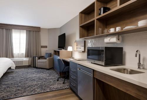 une chambre d'hôtel avec un lit et une cuisine avec un évier dans l'établissement Candlewood Suites Lafayette - River Ranch, an IHG Hotel, à Lafayette