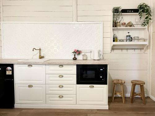 eine weiße Küche mit einer Spüle und einer Mikrowelle in der Unterkunft Taree CBD boutique apartment in Taree