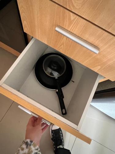 a person is putting a frying pan in a drawer at Departamento amoblado en Parque Urbano in Concepción