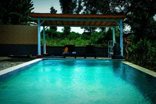 una piscina con cenador y una persona sentada en una silla en Eco Moringa Garden en Banyuwedang