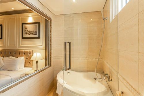 a bathroom with a bath tub and a bed at Silverland Jolie Hotel in Ho Chi Minh City