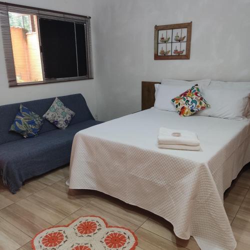 a bedroom with a bed and a blue couch at Casa em Paraty - próximo das cachoeiras! in Paraty
