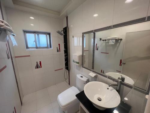 a white bathroom with a sink and a toilet at Ibizakenting Hotel II in Kenting