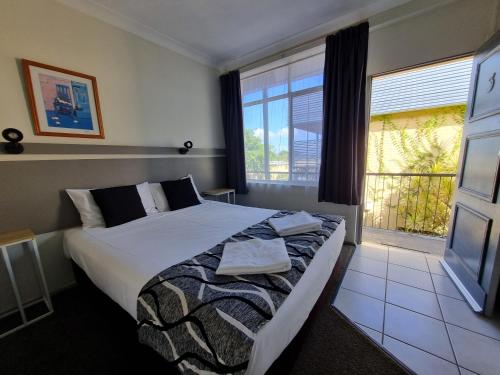 a bedroom with a bed and a large window at Park Drive Motel in Kempsey