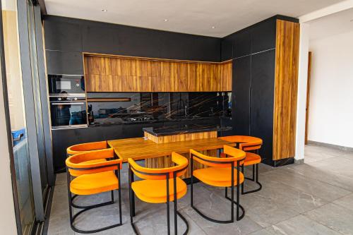 una cocina con mesa de madera y sillas naranjas en Villa luxurieuse neuve Jasmin, en Marrakech