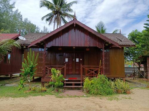 una pequeña casa con techo rojo en Bayu Beach Penarek, en Kampung Penarik