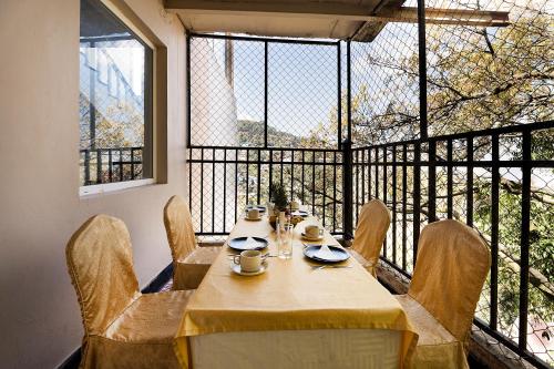 a dining room table with chairs and a large window at EllBee Mussoorie Hills in Mussoorie