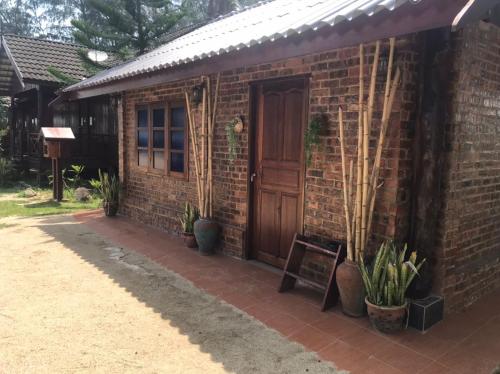 a brick house with a wooden door and some plants at Bayu Beach Penarek in Penarek