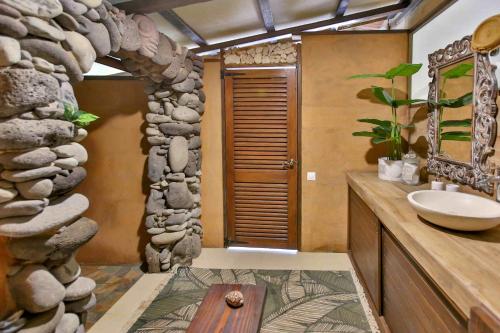 a bathroom with a sink and a stone wall at Soul Rise in Taravao