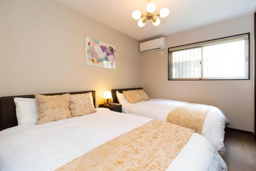 a bedroom with two beds and a window at TY HOUSE 生野 in Osaka