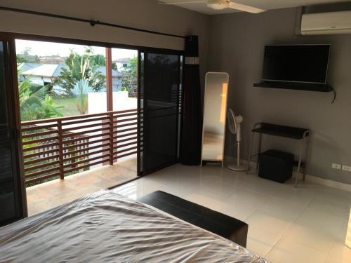 a bedroom with a bed and a balcony with a television at VIP Chain Resort in Rayong